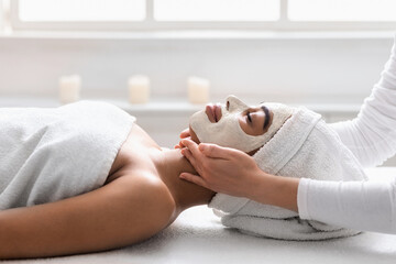 Wall Mural - Beautician massaging black woman chin at spa, side view