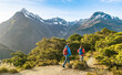 © Maridav - Hiking couple walking on trail at Routeburn Track in New Zealand. Hikers trekking wearing backpacks while tramping on Key Summit Track on vacation at Fiordland National Park, New Zealand.