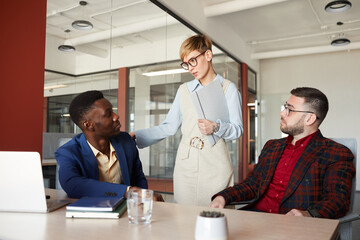 Wall Mural - Portrait of contemporary multi-ethnic business team discussing work project in office, focus on female manager talking to colleagues, copy space