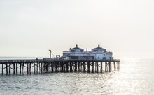  Buildings On A Vintage California Pier In The Early Morning Mist With Sun Glistening Through The Fog On The Ocean