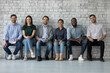 © fizkes - Six skilled potential company employees sit in queue in line smile looking at camera. Multi ethnic young people applicants wait for job interview feels confident. Human resources and staffing concept