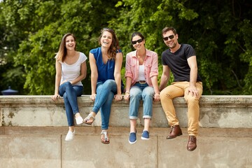 Poster - Happy young people sitting outdoors, smiling. 