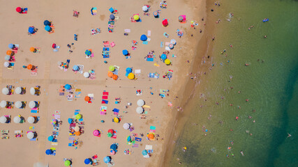 Aerial view of sandy beach with tourists swimming in beautiful clear sea water in Madeira island.