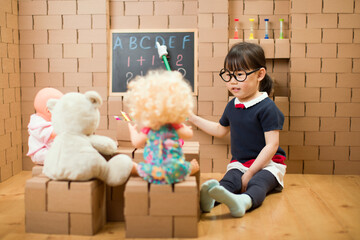 Wall Mural - toddler girl pretend play as a teacher at home