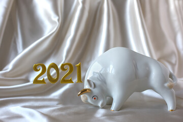 Wall Mural - New Year 2021. White ceramic bull next to inscription of the golden numbers 2021 on beige silk drapery background