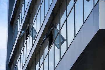 facade of a modern building on a bright Sunny day, blue sky and clouds reflecting in a glass, beautiful exterior of the new building