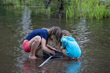 Two Girls With Fishing Net Looking For Tadpoles