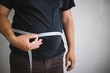 © Vadym - Overweight man measuring waist with measure tape, close up image. Weight loss, motivation, fat burning