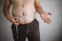 Overweight Man Measuring Waist With Measure Tape, Close Up Image. Weight Loss, Motivation, Fat Burning