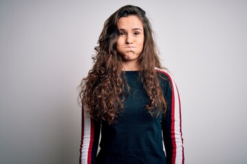 Poster - Young beautiful woman with curly hair wearing casual sweater over isolated white background puffing cheeks with funny face. Mouth inflated with air, crazy expression.