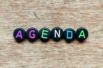 Poster - Black bead with color letter in word agenda on wood background