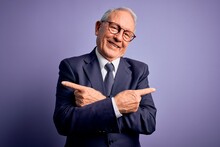 Grey Haired Senior Business Man Wearing Glasses And Elegant Suit And Tie Over Purple Background Pointing To Both Sides With Fingers, Different Direction Disagree