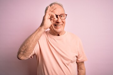 Wall Mural - Grey haired senior man wearing glasses standing over pink isolated background doing ok gesture with hand smiling, eye looking through fingers with happy face.