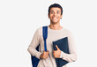 © Krakenimages.com - Young african amercian man wearing student backpack holding binder looking positive and happy standing and smiling with a confident smile showing teeth