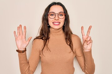 Wall Mural - Young beautiful woman wearing casual turtleneck sweater and glasses over white background showing and pointing up with fingers number seven while smiling confident and happy.