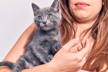 Young beautiful latin woman smilling happy. Standing with smile on face holding adorable cat over isolated white backgroun