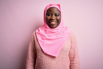 Canvas Print - Young african american plus size woman wearing muslim hijab over isolated pink background with a happy and cool smile on face. Lucky person.