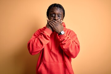 Canvas Print - Young african american sporty man wearing sweatshirt with hoodie over yellow background shocked covering mouth with hands for mistake. Secret concept.