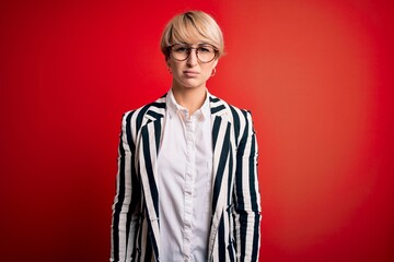 Sticker - Blonde business woman with short hair wearing glasses and striped jacket over red background depressed and worry for distress, crying angry and afraid. Sad expression.