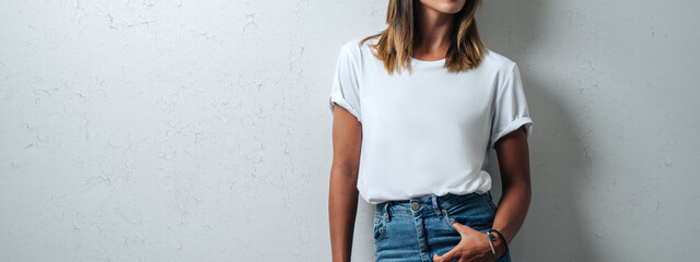 Young woman in white blank t-shirt wearing glasses, grunge wall, horizontal studio portrait. Wide screen, panoramic