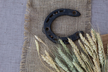 Wall Mural - On a jute napkin lies an old horseshoe and ears of wheat.