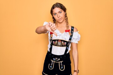 Wall Mural - Young beautiful blonde german woman with blue eyes wearing traditional octoberfest dress looking unhappy and angry showing rejection and negative with thumbs down gesture. Bad expression.