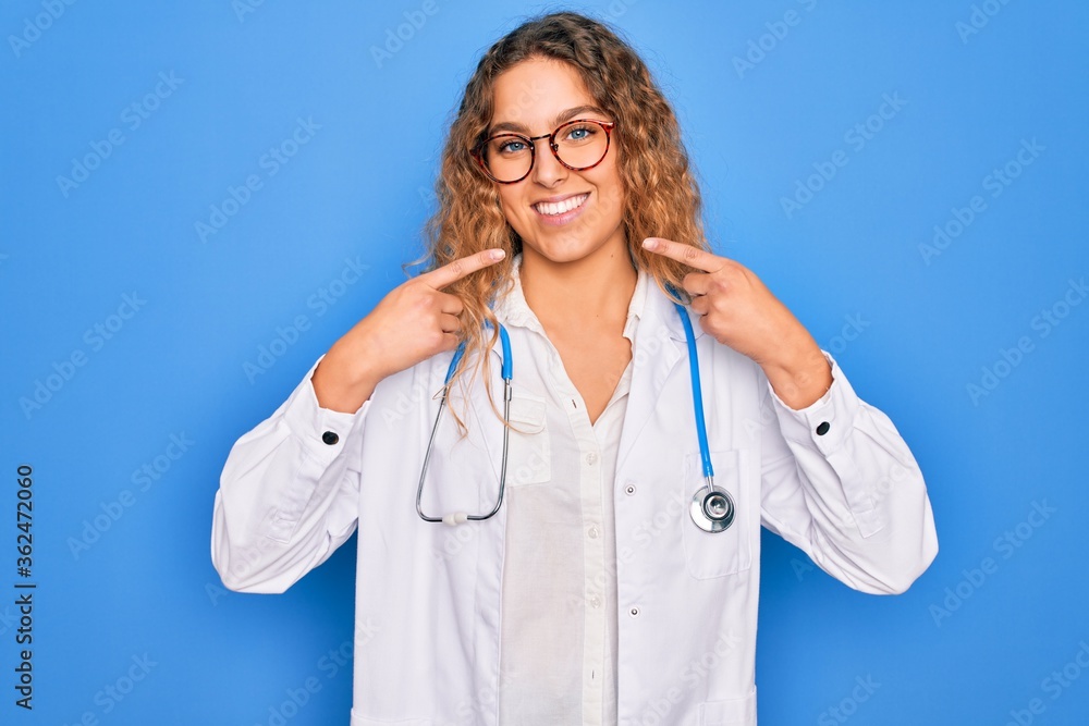 Young beautiful blonde doctor woman with blue eyes wearing coat and ...