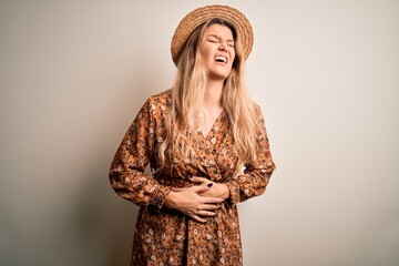 Poster - Young beautiful blonde woman wearing summer dress and hat over isolated white background with hand on stomach because nausea, painful disease feeling unwell. Ache concept.