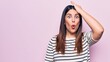 Young beautiful brunette woman wearing casual striped t-shirt over isolated pink background surprised with hand on head for mistake, remember error. Forgot, bad memory concept.