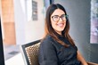 © Krakenimages.com - Young beautiful brunette woman wearing glasses smiling happy and confident. Sitting with smile on face at restaurant