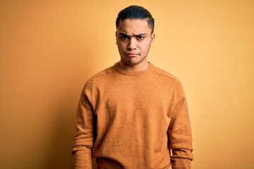 Wall Mural - Young brazilian man wearing casual sweater standing over isolated yellow background skeptic and nervous, frowning upset because of problem. Negative person.