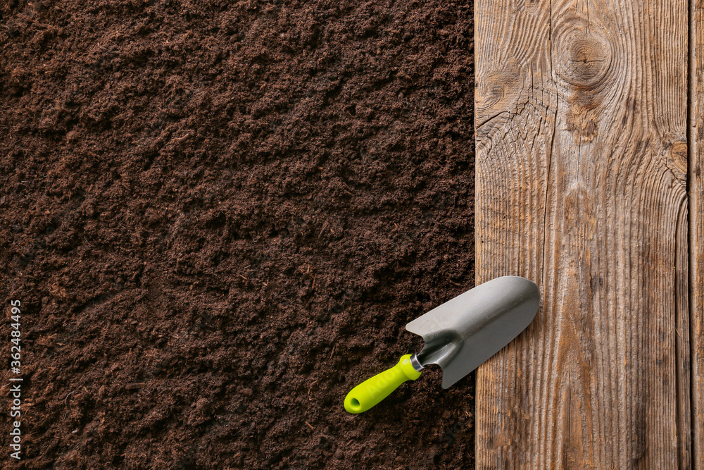 Wooden surface and shovel on soil