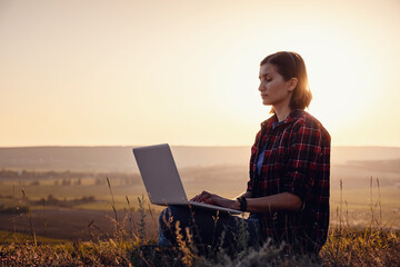 Girl working on her computer on the top of the mountain