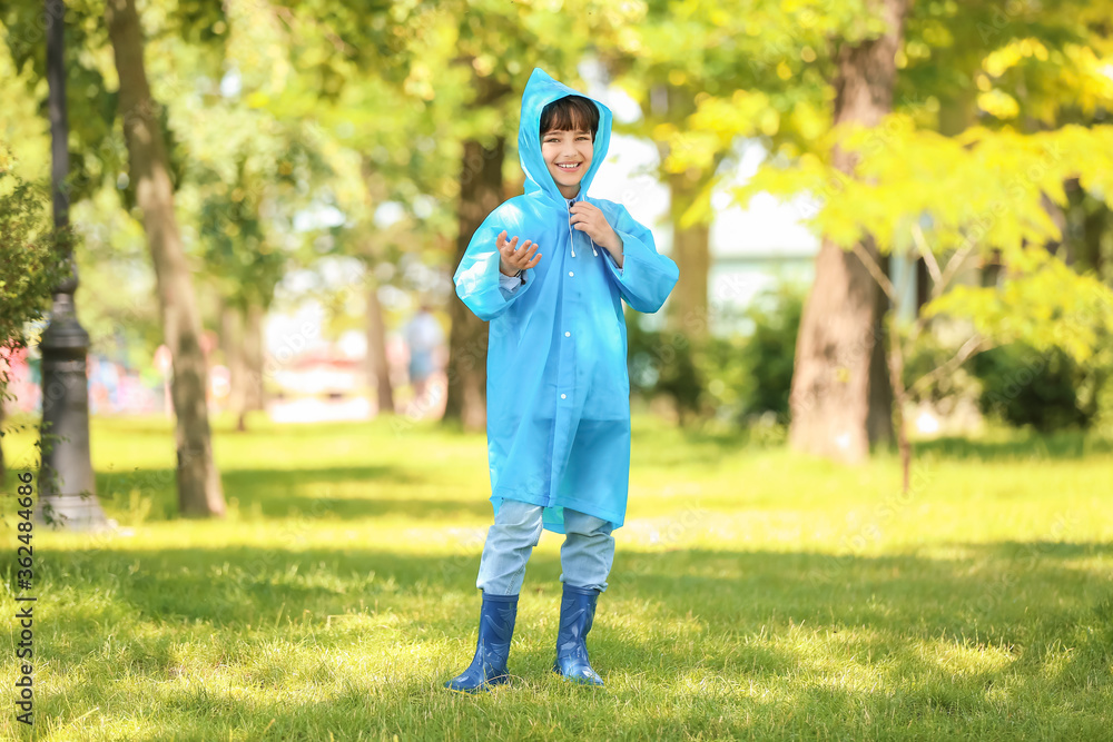 Cute little boy wearing raincoat in park