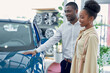 © alfa27 - just imagine us on the road. portrait of happy african american couple checking out a car in modern dealership, they choose new car together