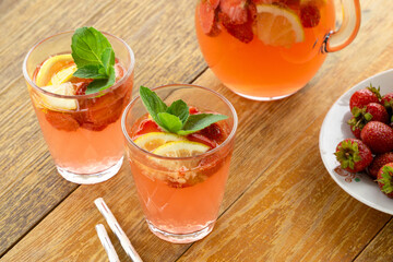 Wall Mural - Summer pink lemonade with strawberries and mint in glasses on a wooden background