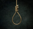 Rope noose for hangman made of natural fiber rope on a grainy gray wall. Hemp rope knot for gallows and Hang man over black concrete wall. The rope noose for homicide or commit suicide concept.