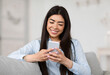 © Prostock-studio - Smiling Asian Girl Browsing Social Networks On Smartphone At Home, Enjoying Weekend