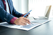 © Orathai - Hand of businessmen are planning business investments related to shares By analyzing and calculating the stock market for marketing profits