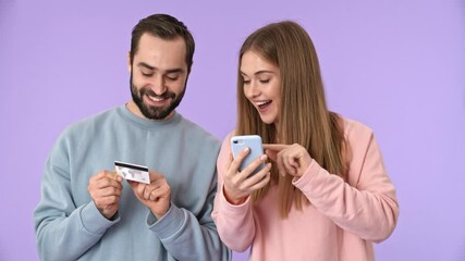 Sticker - Cheerful young couple making a purchases on smartphone with credit card and rejoicing over purple background