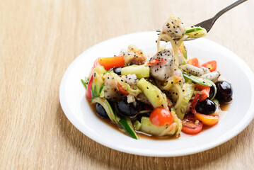 Spicy fruit and vegetables salad on white plate eating by fork, Healthy vegan food