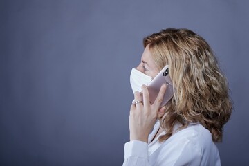 Poster - Blonde female doctor with a medical robe and face mask talking to the phone