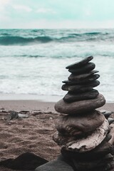 Wall Mural - Stone balancing on the sandy beach with the wavy beautiful ocean