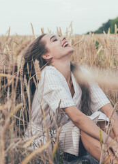 portrait of a girl of model appearance in wheat, a girl sits in a wheat field and smiles