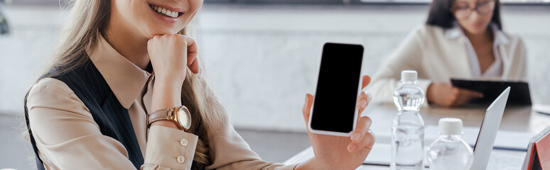 Poster - panoramic crop of businesswoman holding smartphone with blank screen