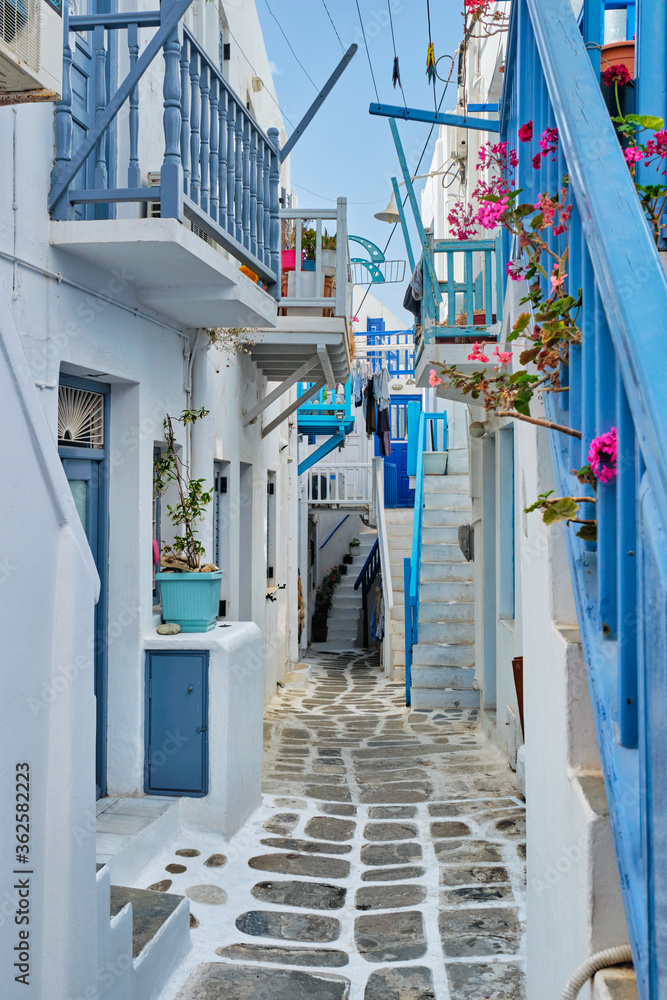 Picturesque scenic narrow Greek streets with traditional whitewashed houses with blue doors windows of Mykonos town in famous tourist attraction Mykonos island, Greece - obrazy, fototapety, plakaty 