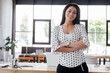© LIGHTFIELD STUDIOS - cheerful businesswoman standing with crossed arms in office