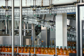 Wall Mural - Plastic bottles with juice on conveyor line or belt in modern beverage factory.
