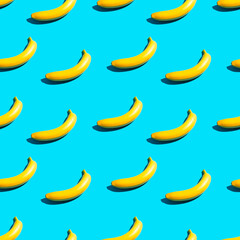 Wall Mural - Seamless pattern of bright yellow bananas on a blue background. Creative design background. The concept of summer, tropics and healthy food.