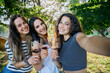 Friends taking a selfie photo in a relax moment - Young millennial women toasting in a park with red wine glasses in a tasting of a restaurant - Group of people having fun together